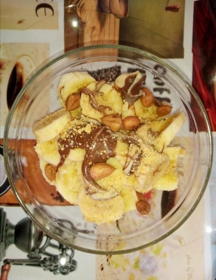 a plate with bannanas, hazelnuts, cream and crushed biscuits