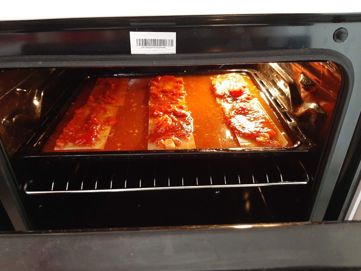 lasagna crusts with tomato sauce in an oven