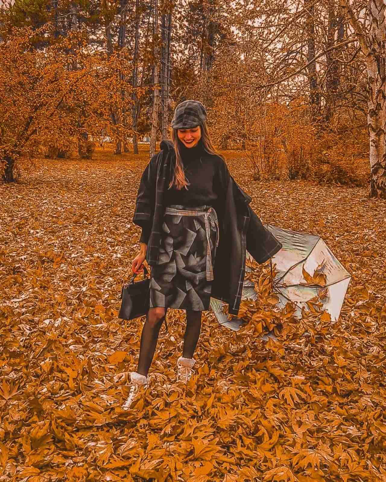 Evgenija Jovanova in a pile of golden autumn leaves, holding a white umbrella